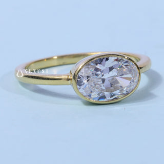 Bezel Oval Cut East West Moissanite Engagement Ring resting on its side showing the slim band