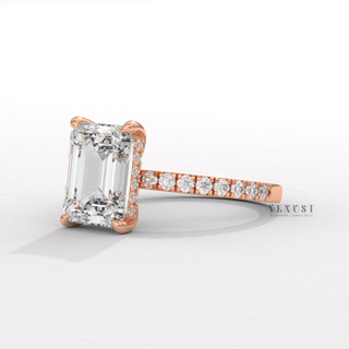 Low-angle view of a emerald cut moissanite engagement ring with a hidden halo and pave band