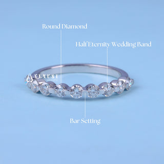 Delicate round half eternity moissanite wedding band shown on a finger