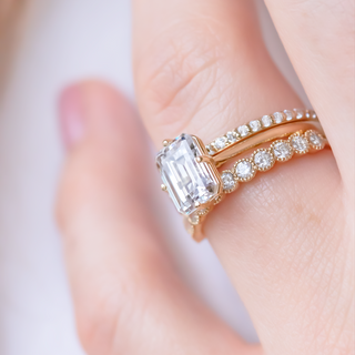Delicate round full eternity moissanite wedding band shown on a finger