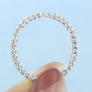 Modern round full eternity moissanite wedding band shown on a finger