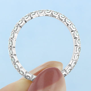 Refined round full eternity moissanite wedding band shown on a finger