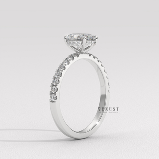 Studio shot of a oval cut moissanite engagement ring with a hidden halo and half pave band on a plain backdrop