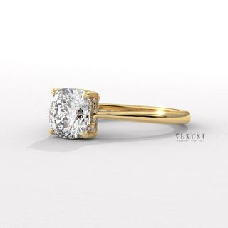 Studio shot of a cushion cut moissanite engagement ring with a hidden halo and cathedral setting on a plain backdrop