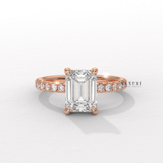 Studio shot of a emerald cut moissanite engagement ring with a pave band on a plain backdrop