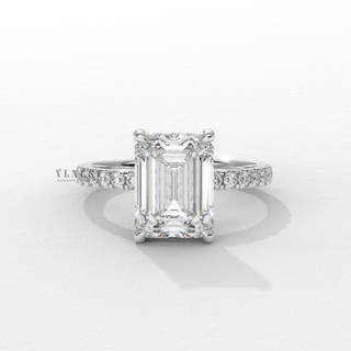 Studio shot of a emerald cut moissanite engagement ring with a hidden halo and pave band on a plain backdrop