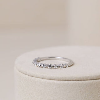 Shimmering round half eternity moissanite wedding band shown on a finger