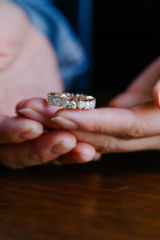 Stunning heart full eternity moissanite wedding band shown on a finger