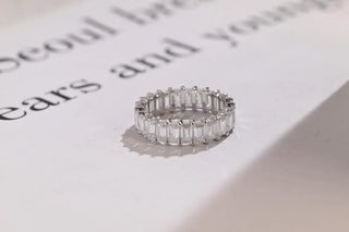 Delicate emerald full eternity moissanite wedding band shown on a finger