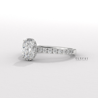 Tilted view of a oval cut moissanite engagement ring with a hidden halo and half pave band showing its sparkle