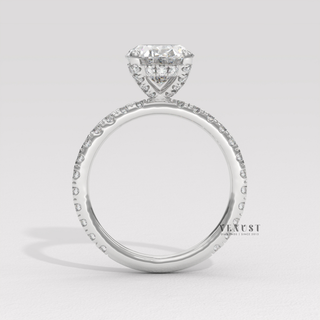 Angled view of a oval cut moissanite engagement ring with a pave band catching the light