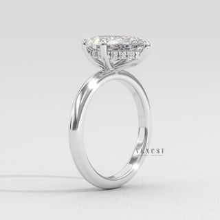 Studio shot of a pear cut moissanite engagement ring in a hidden halo solitaire setting on a plain backdrop