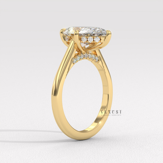 Studio shot of a pear cut moissanite engagement ring with a hidden halo and cathedral setting on a plain backdrop