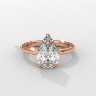 Pear cut moissanite engagement ring in a hidden halo solitaire setting photographed on a white background