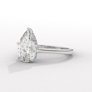 Hand model wearing a pear cut moissanite engagement ring with a hidden halo and cathedral setting