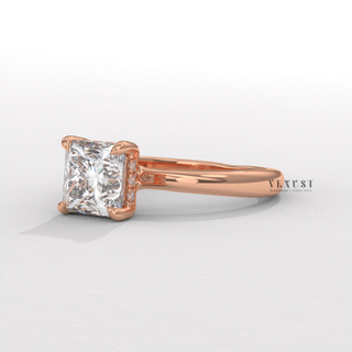 Studio shot of a princess cut moissanite engagement ring in a hidden halo solitaire setting on a plain backdrop
