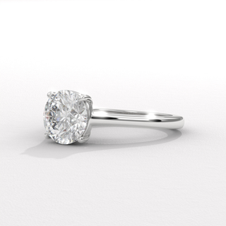 Studio shot of a round cut moissanite engagement ring with a hidden halo and cathedral setting on a plain backdrop