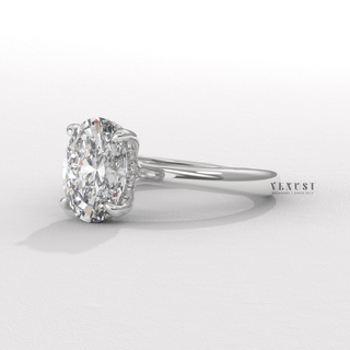 Studio shot of a oval cut moissanite engagement ring in a hidden halo solitaire setting on a plain backdrop