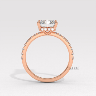 Front view of a radiant cut moissanite engagement ring with a pave band under soft light